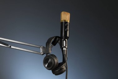 Koyu arka planda mikrofon ve kulaklıkla kalın, düşük açılı görüş. Ses kaydı ve takviye