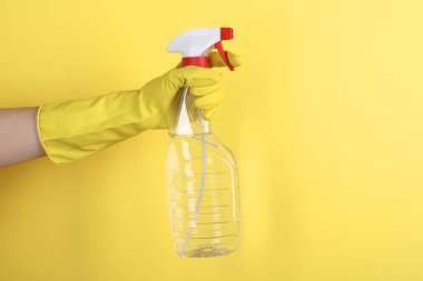 Sarı arka planda plastik sprey şişesi tutan kadın, yakın plan. Metin için boşluk