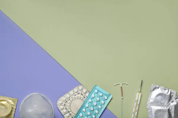 Contraceptive pills, condoms, intrauterine device and thermometer on color background, flat lay and space for text. Different birth control methods