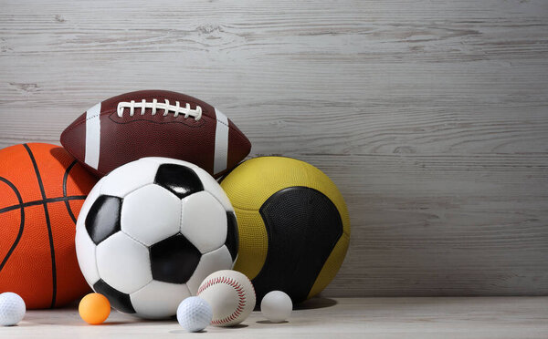Many different sport balls on white wooden background, space for text