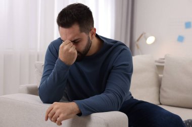 Evdeki kanepede baş ağrısı çeken bir adam.