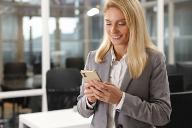Ofisinde akıllı telefonu olan gülümseyen bir kadın, mesaj atmak için yer var. Avukat, iş kadını, muhasebeci ya da müdür.