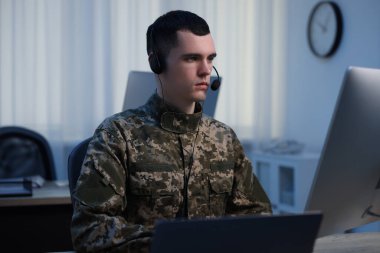 Askerlik. Ofiste çalışan kulaklıklı genç asker.