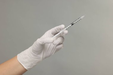 Gri arka planda tıbbi şırınga tutan doktor, yakın plan.