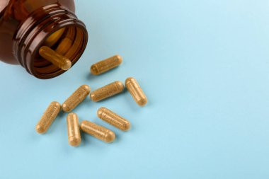Açık mavi arka planda şişe ve vitamin kapsülleri, yakın plan. Metin için boşluk
