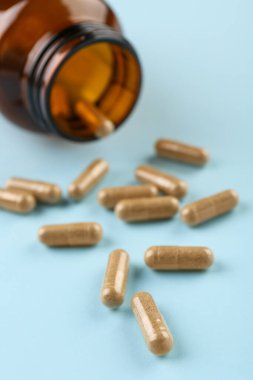 Açık mavi arka planda şişe ve vitamin kapsülleri, yakın plan