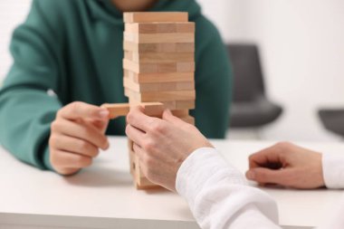 Beyaz masada Jenga kulesi oynayan insanlar, yakın plan.