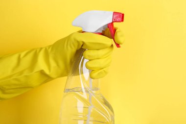 Sarı arka planda plastik sprey şişesi tutan kadın, yakın plan. Metin için boşluk