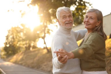 Sevecen yaşlı çift gün batımında dışarıda dans ediyor, mesajlaşmak için yer var.