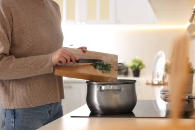 Mutfakta çorbayla maydanoz karıştıran kadın, yakın plan.