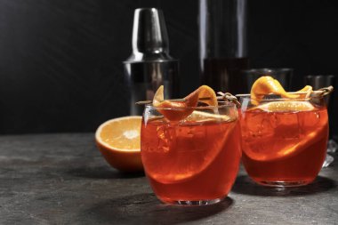 Aperol sprey kokteyli, buz küpleri ve gri desenli masada portakal dilimleri, metin için boşluk.