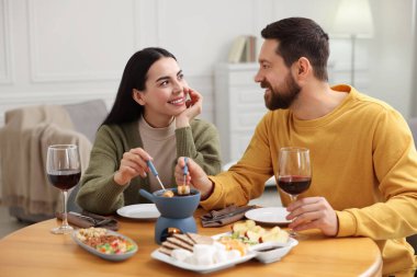 Sevgili çift evde romantik bir buluşma sırasında çikolatalı fondü yiyor.