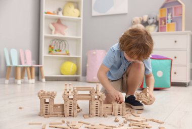 Odanın zemininde ahşap inşaatla oynayan küçük bir çocuk, mesaj için yer var. Çocuk oyuncağı