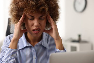 İş yerinde baş ağrısı çeken bir kadın.