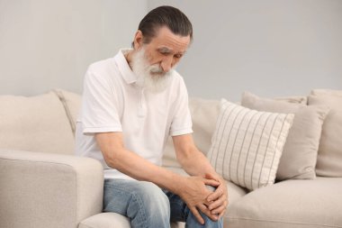 Evdeki kanepede diz ağrısı çeken son sınıf öğrencisi. Romatizma belirtileri