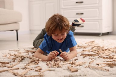Evdeki halıda ahşap inşaat setiyle oynayan sevimli küçük çocuk. Çocuk oyuncağı