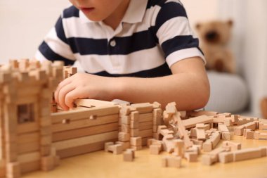 Küçük çocuk odasındaki masada ahşap inşaatla oynuyor, yakın plan. Çocuk oyuncağı