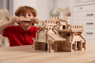 Odada tahta kaleyle oynayan şirin bir çocuk, seçici bir odak. Çocuk oyuncağı