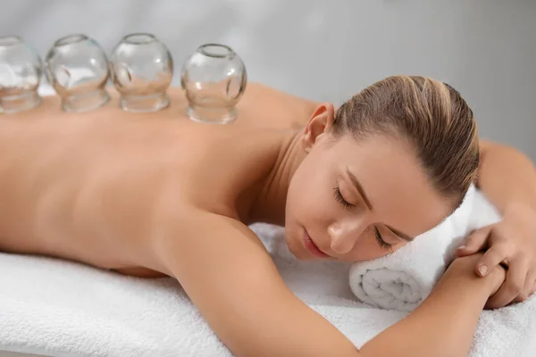 Cupping therapy. Woman with glass cups on massage couch in spa salon