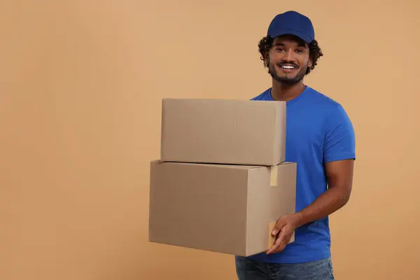 Happy courier with parcels on light brown background, space for text