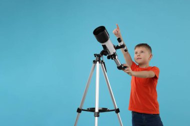 Teleskopu açık mavi arka planda bir şeye bakan sevimli küçük çocuk, mesaj için yer var.