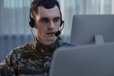 Askerlik. Ofiste çalışan kulaklıklı genç asker.
