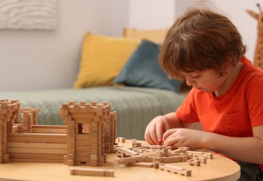 Küçük çocuk masadaki ahşap inşaatla oynuyor. Çocuk oyuncağı