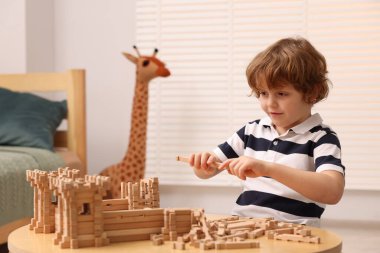 Odadaki ahşap inşaat setiyle oynayan sevimli küçük çocuk. Çocuk oyuncağı