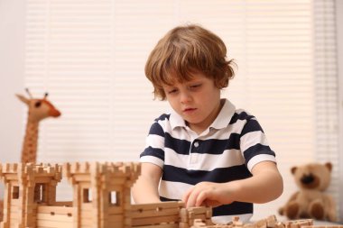 Odadaki ahşap inşaat setiyle oynayan sevimli küçük çocuk. Çocuk oyuncağı