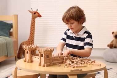 Odadaki ahşap inşaat setiyle oynayan sevimli küçük çocuk. Çocuk oyuncağı