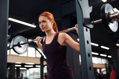 Spor salonunda halter eğitimi alan atletik genç bir kadın.