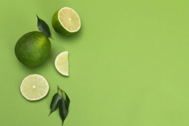 Yeşil arka planda taze limon ve yapraklarla bezenmiş düz bir kompozisyon. Metin için boşluk