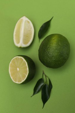 Yeşil zemin üzerinde taze limon ve yapraklar ile düz bileşim yatıyordu