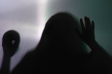 Gri arka planda kafatası olan tüyler ürpertici bir hayalet silueti.