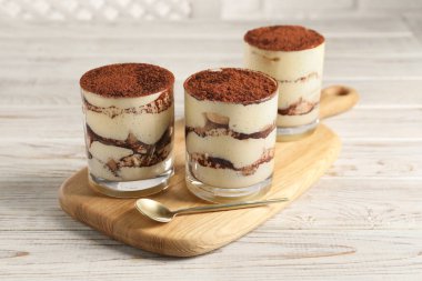 Gözlüklü lezzetli tiramisu ve açık ahşap masada kaşık.