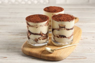 Gözlüklü lezzetli tiramisu ve açık ahşap masada kaşık.