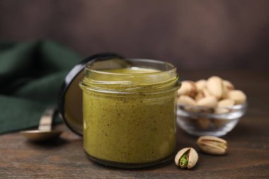 Kavanozda fıstıklı krema ve ahşap masada fındıklar, yakın plan.