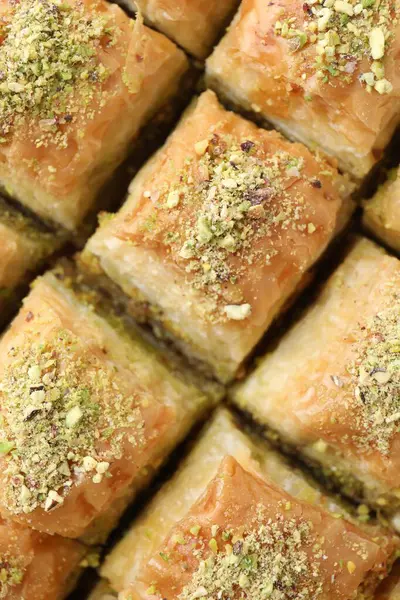 Delicious fresh baklava with chopped nuts as background, top view. Eastern sweets