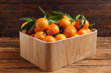 Tahta masada yeşil yapraklı taze mandalinalar.