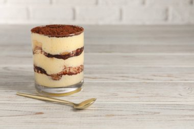 Cam içinde nefis tiramisu ve açık ahşap masada kaşık. Metin için boşluk