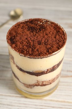 Hafif ahşap masada cam içinde nefis tiramisu, yakın plan.