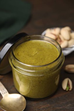 Kavanozda fıstıklı krema ve ahşap masada fındıklar, yakın plan.