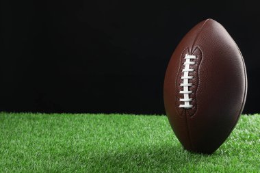 Amerikan futbol topu yeşil çimlere karşı siyah arkaplan, yazı için boşluk