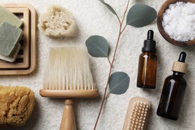 Açık gri desenli masa üzerinde farklı spa ürünleri ve okaliptüs dalları içeren düz bir kompozisyon.