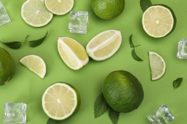 Taze limon, buz küpleri ve yeşil arka planda yapraklarla düz bileşim