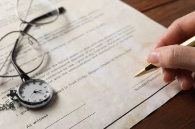 Ahşap masada son arzusunu ve vasiyetini imzalayan kadın, yakın plan.