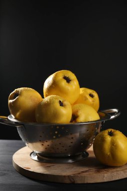 Lezzetli quinces 'ler siyah ahşap masada metal kevaşe içinde su damlaları