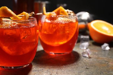 Aperol sprey kokteyli, buz küpleri ve portakal dilimleri gri desenli masada, yakın plan.