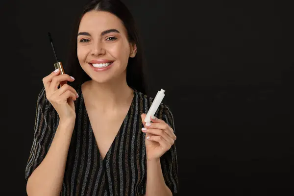 stock image Beautiful young woman with mascara on black background, space for text