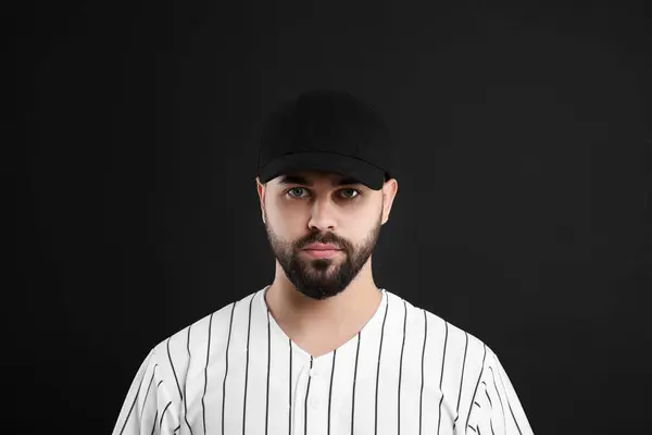 Man in stylish baseball cap on black background
